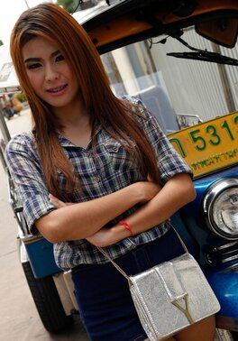 Exotic teen with red hair demonstrates her braces while posing near rickshaw
