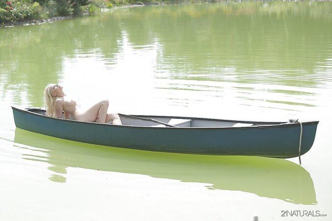 Slutty blonde girl in a birthday suit rests by a lake and masturbates