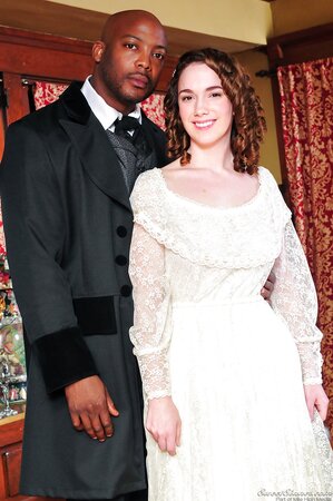 Pale-skinned girl in old-fashioned white dress kisses black man in a suit