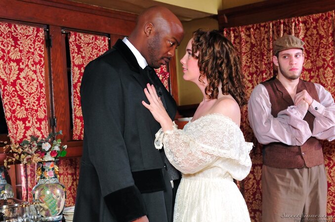 Pale-skinned girl in old-fashioned white dress kisses black man in a suit