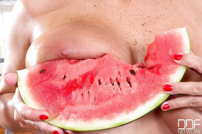 Cute seductress eats watermelon squeezing its juice over hr big naked knockers