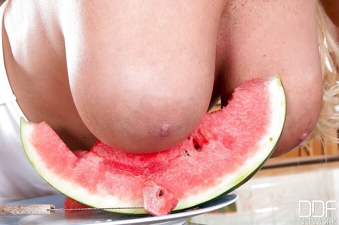 Cute seductress eats watermelon squeezing its juice over hr big naked knockers