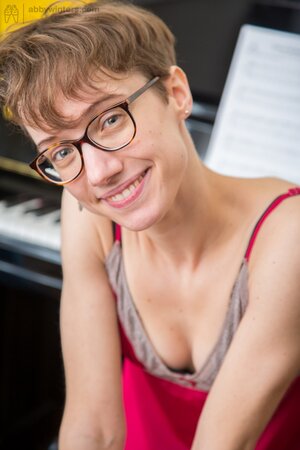 Ugly short-haired musician with glasses teases herself while playing piano