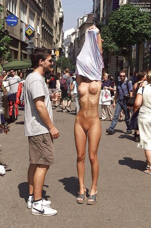 Whore in high heels gets naked and poses in the nude on the crowded street