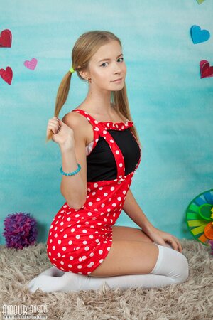 Young woman in a polka-got red dress gets nude in her infantile room