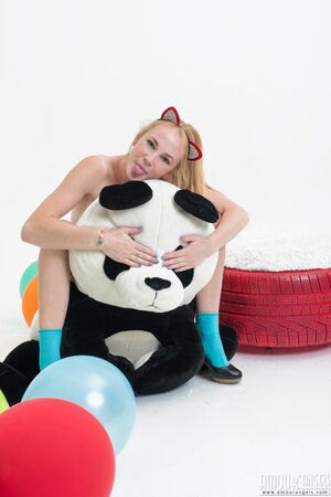 Love with pussy ears hugs and rides a plush panda with balloons in her hands