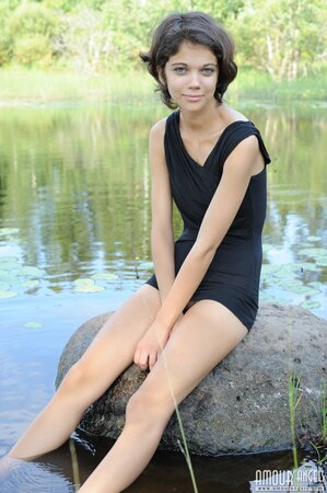 Short-haired babe seductively takes off black outfit while sitting by the pond