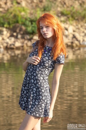 Free-spirited redhead becomes closer with the nature by relaxing nude near river