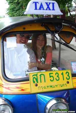 Joyful Thai minx poses near white fellow and his impressive auto rickshaw