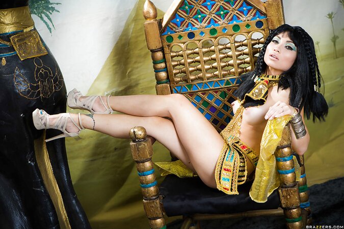 Oriental girl plays the role of Cleopatra posing on a golden throne