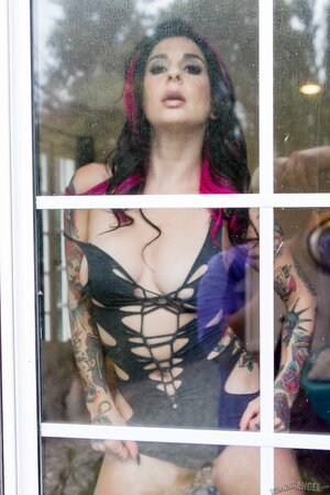 Porn queen strips in front of the glass door and continues posing on the sofa