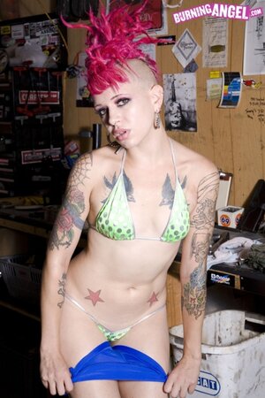 Alt girl with bizarre pink hairstyle is possessor of tattoos and pierced nipples