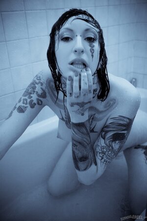 Female with a tattooed body takes a shower and brandishes her private zones