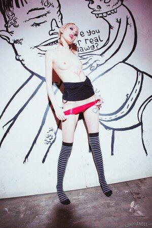 Small-tittied skinny girl in striped over-the-knee socks poses by graffiti wall