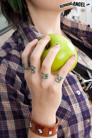 Tattooed coed with green locks eats an apple and fingers vagina on the floor