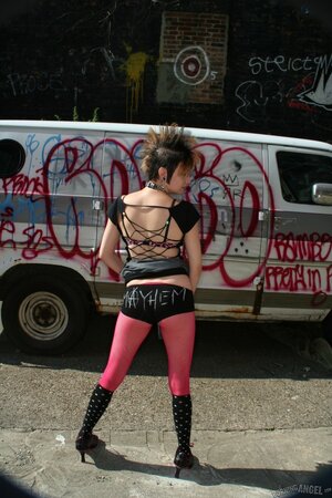 Sexy punk woman with a mohawk pulls her pink pantyhose down to show the vagina