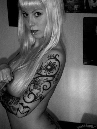 Blonde woman with tattooed body poses naked in the black and white
