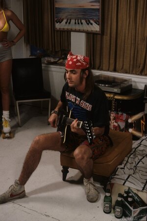 Guy in red bandana plays guitar pretty well but girls are interested in threesome