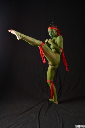 Girl in the image of a naked warrior covered in green paint in combat poses