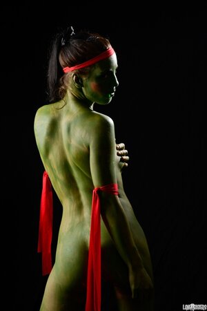 Girl in the image of a naked warrior covered in green paint in combat poses