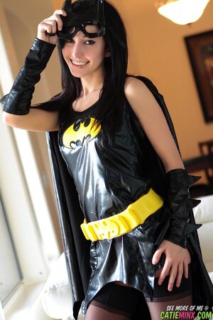 Black-haired fan of cosplay takes off Batman costume and poses naked