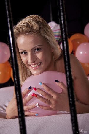 Winsome blonde smiles while stripping naked in the room with balloons