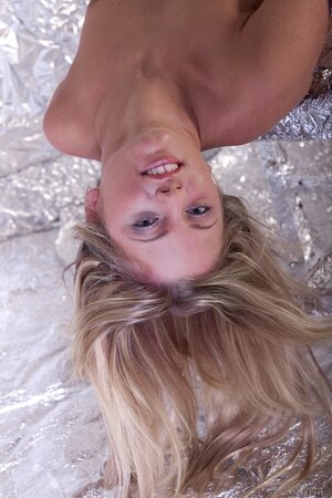 Adorable blonde seductively strips naked in strange room covered with foil