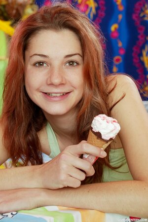 Pleasant girl with red hair eats ice cream and replaces it with the pink vibrator