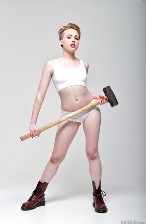Pale-skinned bitch with short red hair and tongue piercing holds sledgehammer