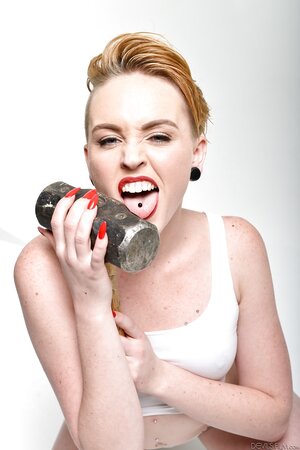 Pale-skinned bitch with short red hair and tongue piercing holds sledgehammer