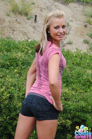 Young blonde charmer playfully demonstrates small tits and cute booty outdoors