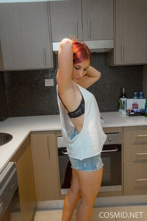 Slender redhead in jean shorts poses with her perky boobs and shaved pussy naked