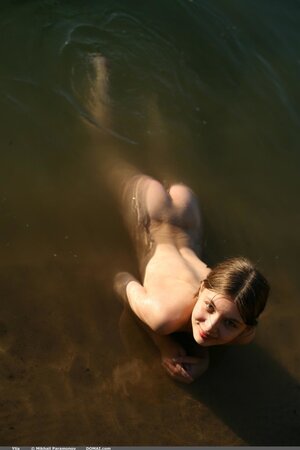 Teen with a nice face and slender body enters the water wearing no swimsuit
