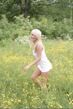 Adorable blonde with juicy tits strips naked in the field full of yellow flowers