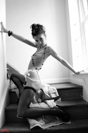 Elegant skinny teen takes off raincoat to pose topless in stockings and lingerie