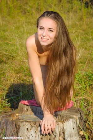 Winsome young lady with long hair enjoys modeling naked in the open air