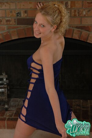 Lustful teen blonde poses in a sexy way wearing cute dress by the fireplace