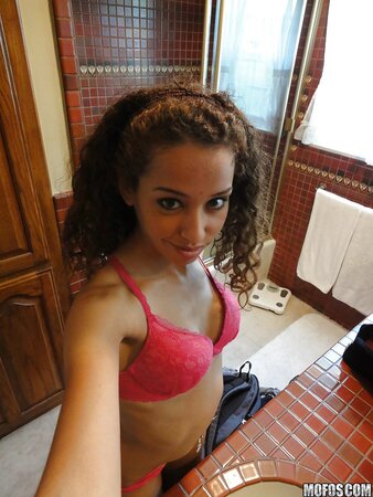 Latina with curly hair is taking sexy selfies while in lingerie
