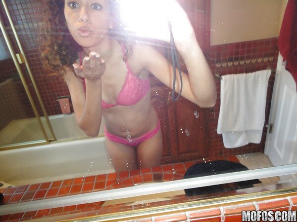 Latina with curly hair is taking sexy selfies while in lingerie