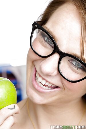 Joyful college girl with glasses during lesson feels desire to touch her peach