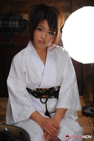 Cute young Japanese woman in a kimono participates in erotic photo session