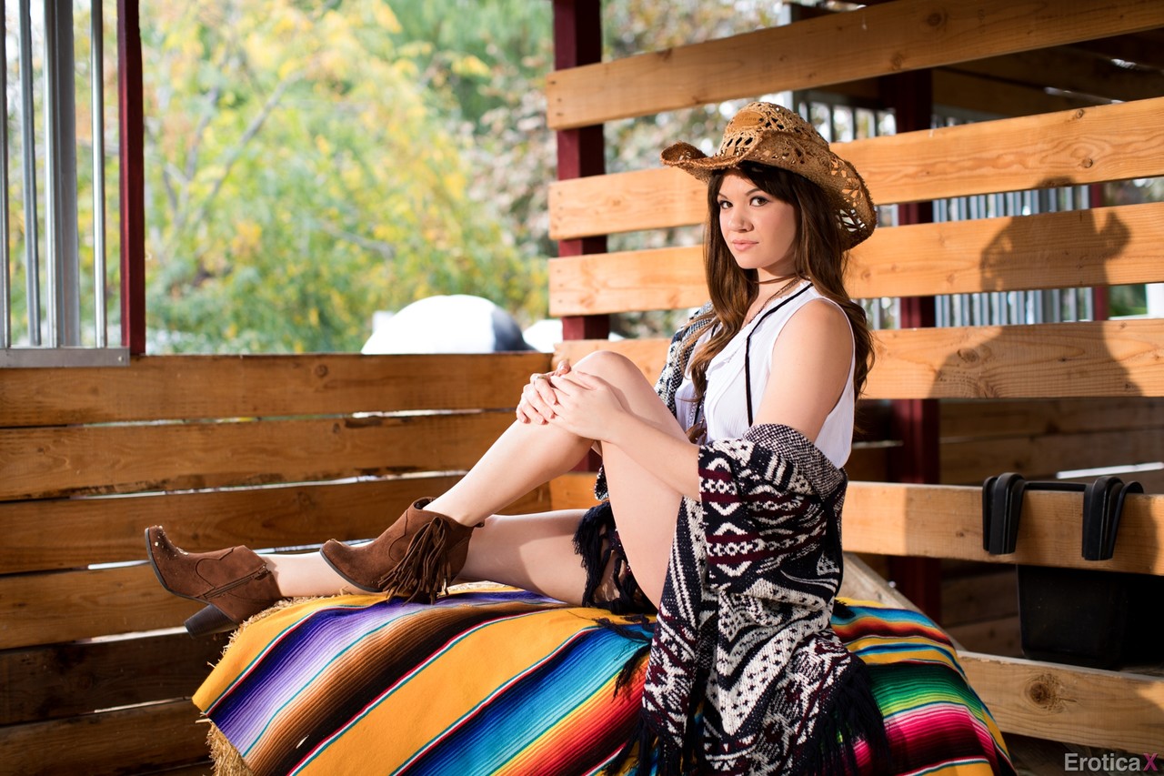 Cowgirl comes to the barn where she poses after stripping down to boots.