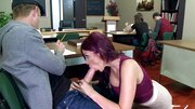A redhead that is wearing glasses is doing a blow job in the classroom